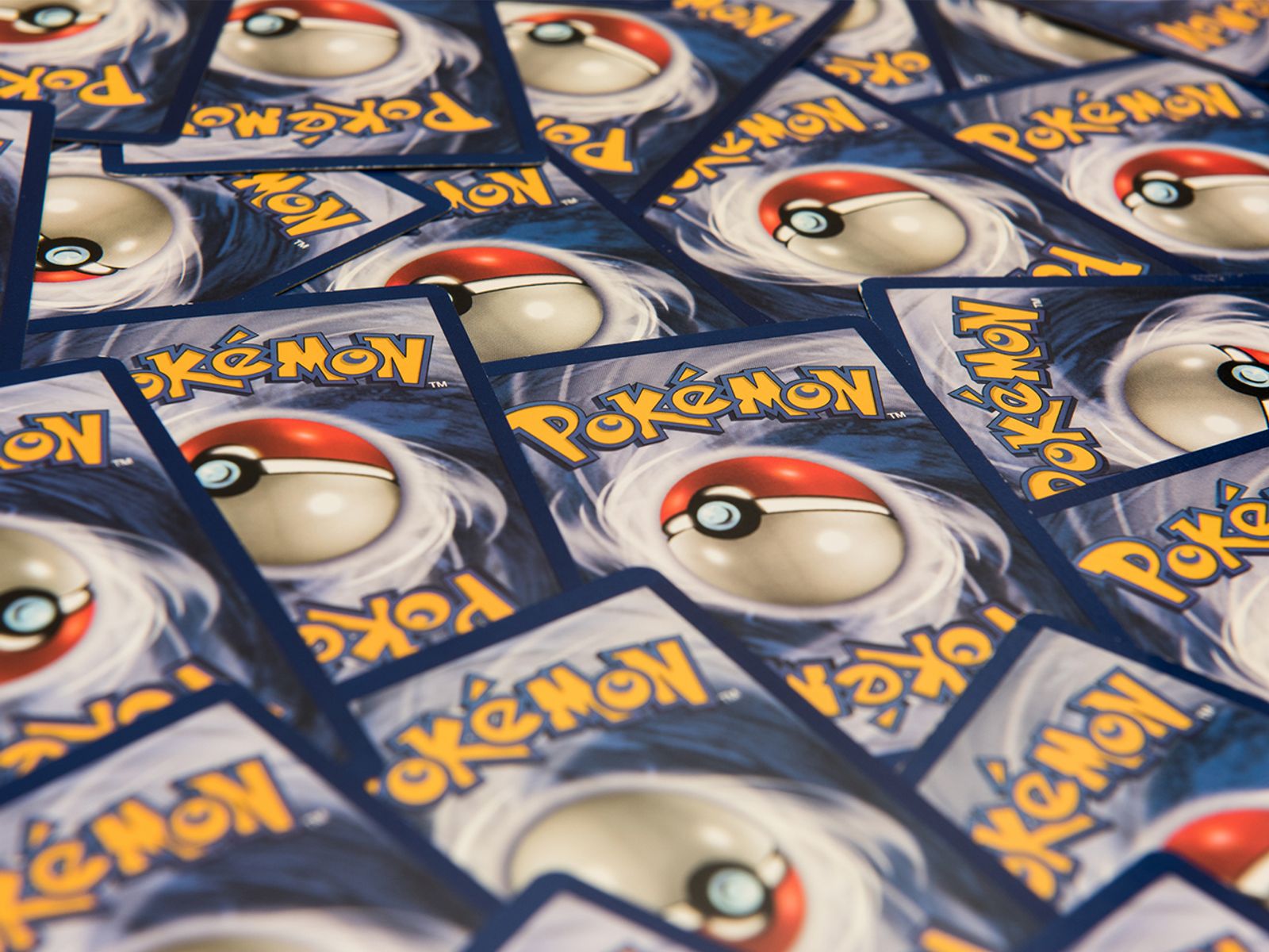 A pile of colourful Pokémon trading cards on a table, featuring classic characters and shiny holographic designs that appeal to both new fans and nostalgic collectors.