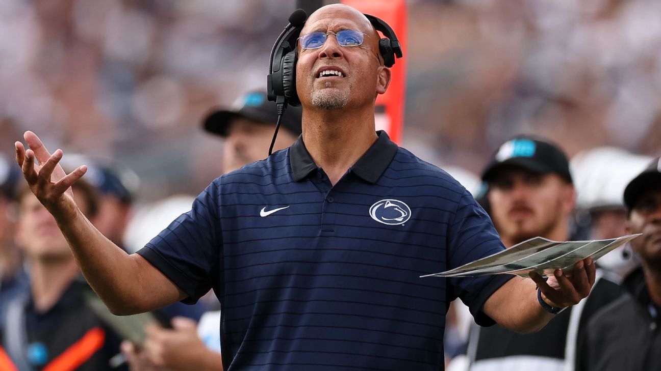James Franklin standing on a football field, looking up at the sky, deep in thought.