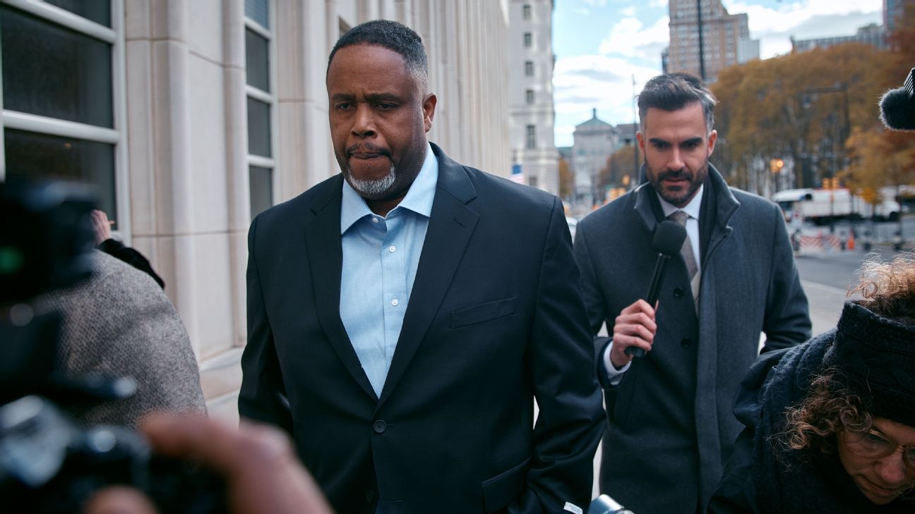 Damon Jones arriving at court wearing a dark suit and tie, looking serious as he walks past photographers.