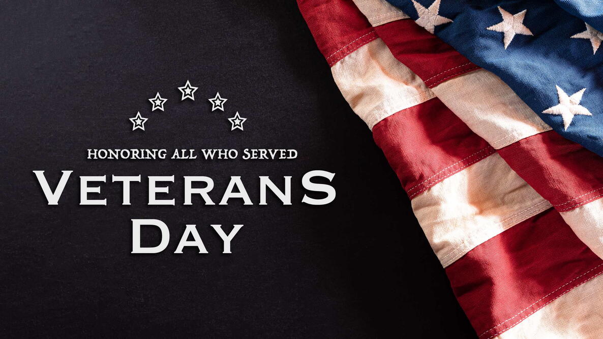 American flag waving with “Veterans Day 2025” text over a dark background.