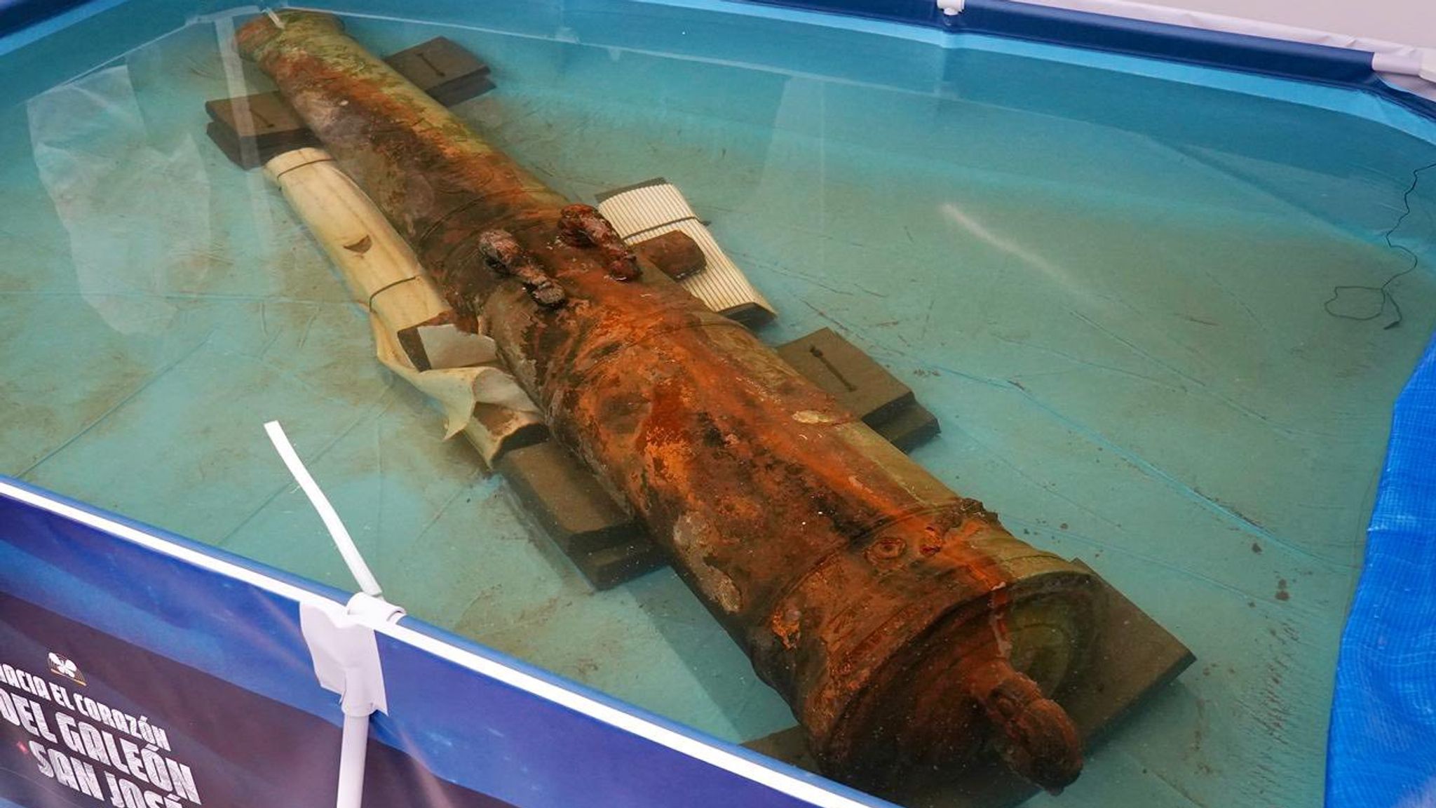 Underwater image of the San José shipwreck cannon being carefully lifted by researchers, covered in centuries-old marine growth.