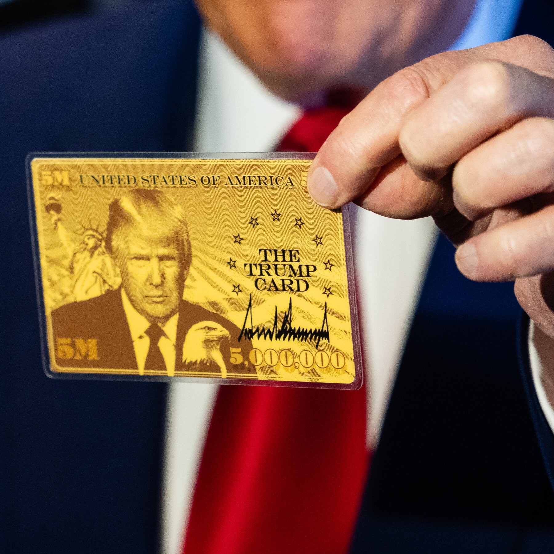 Donald Trump holding the $1 million ‘Gold Card’ visa during an announcement, highlighting the new premium immigration program offering fast-tracked U.S. residency.