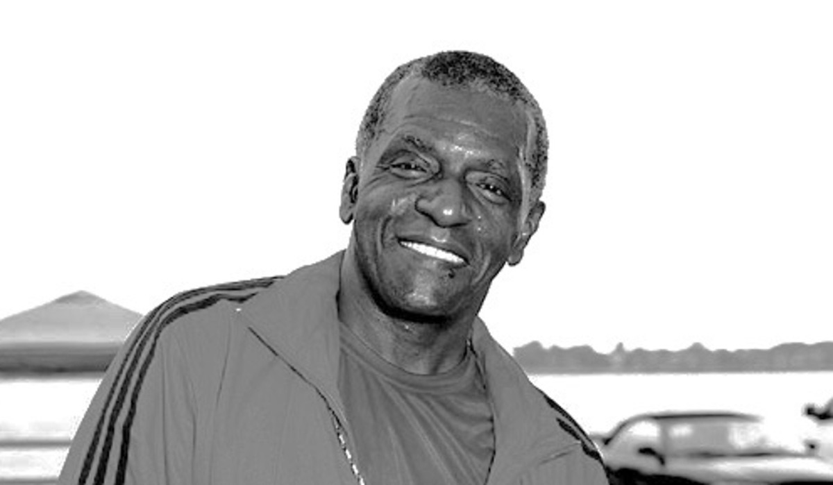 Black and white portrait of Carl Carlton smiling while performing, showcasing his iconic 1980s style.