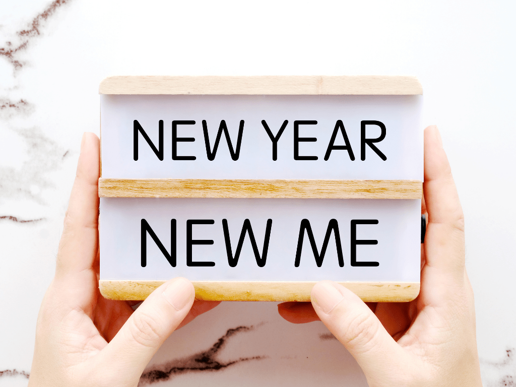Two hands holding a sign that reads "New Year New Me," symbolizing goal setting and personal growth for 2026.