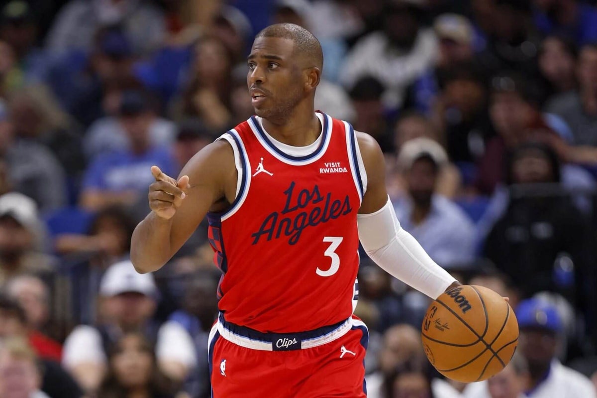 Chris Paul dribbling the basketball in a red Los Angeles Clippers jersey during a game, demonstrating his playmaking skills.