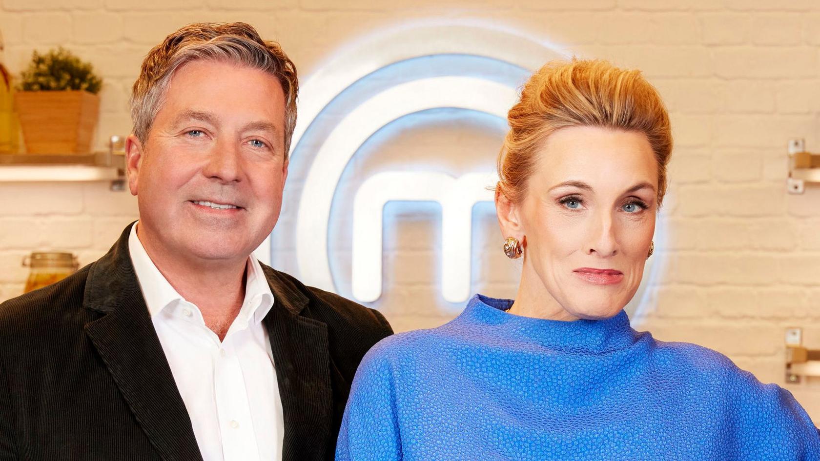 John Torode standing next to Grace Dent, smiling, on the set of MasterChef.