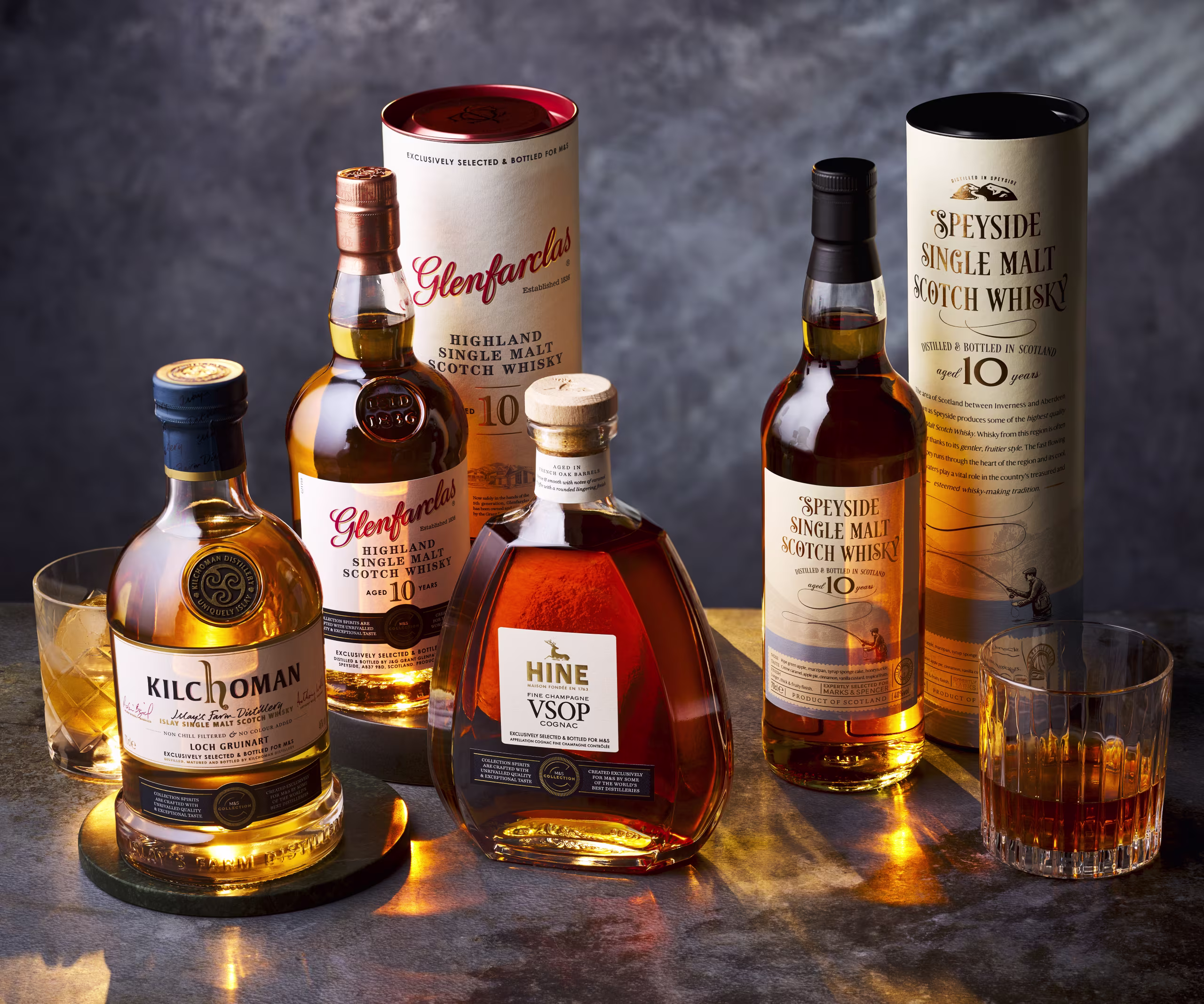 A selection of festive whiskies arranged on a wooden table with holiday decorations and candles.