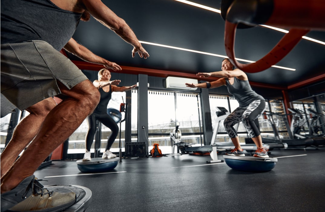 People using balance boards in a group fitness class, engaging their core and improving stability.