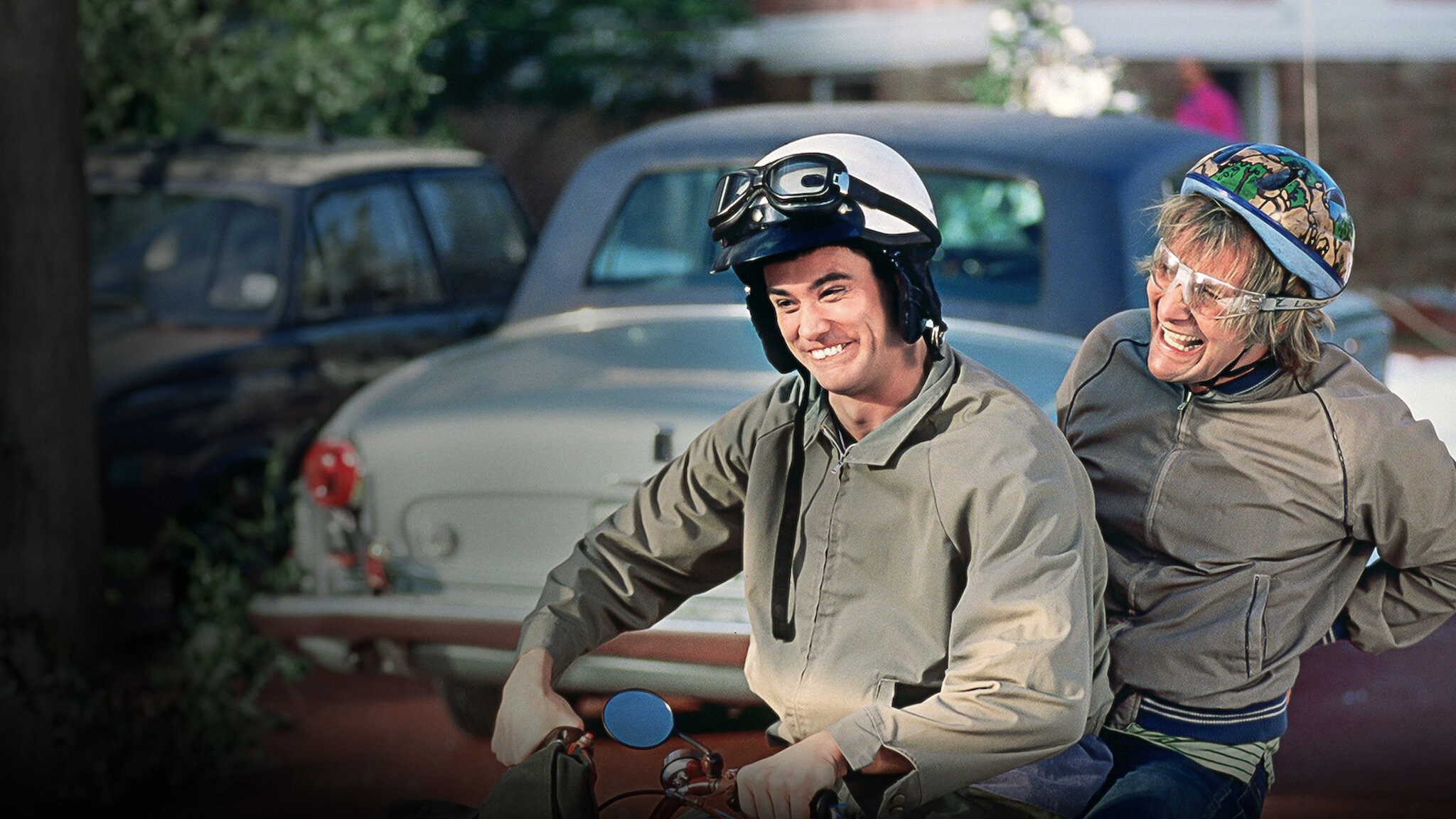 Jim Carrey and Jeff Daniels riding a motorbike together in Dumb and Dumber, capturing a comedic moment from the film.