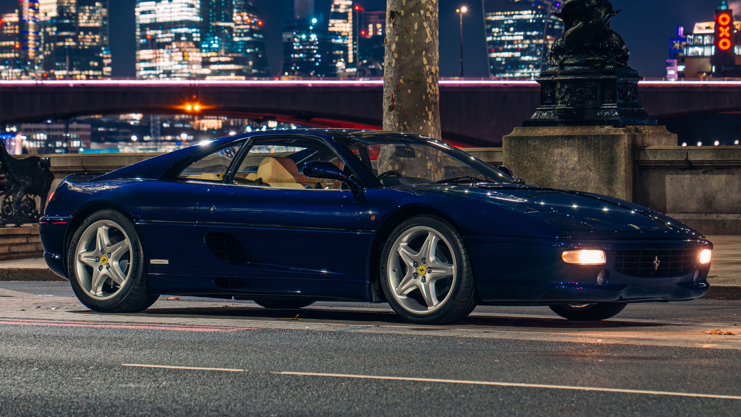 Blue Ferrari owned by Chris Rhea parked with a city skyline visible in the background.