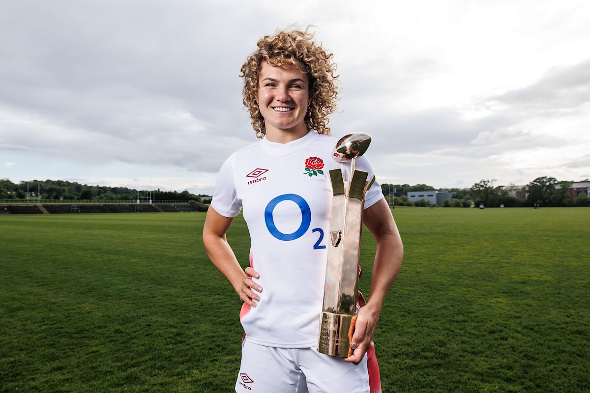 Ellie Kildunne holding a rugby trophy, beaming with pride after England’s Women’s Rugby World Cup victory, symbolizing her impact on the tournament.