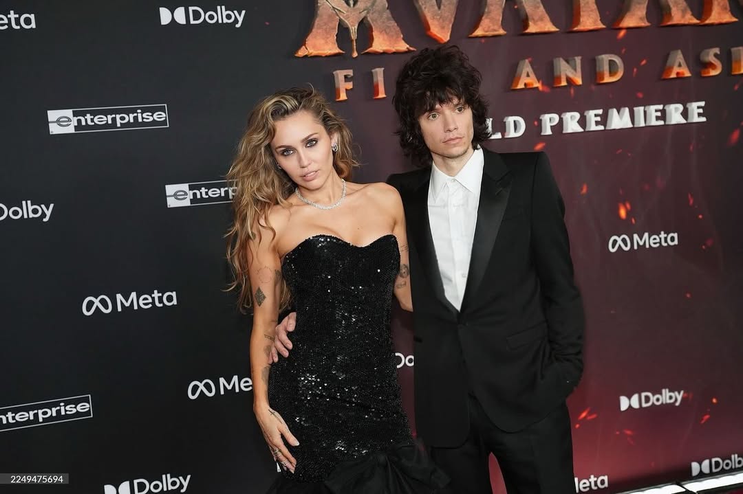 Miley Cyrus and Maxx Morando posing together on the red carpet at the Avatar: Fire and Ash world premiere, with Cyrus’ engagement ring visible.