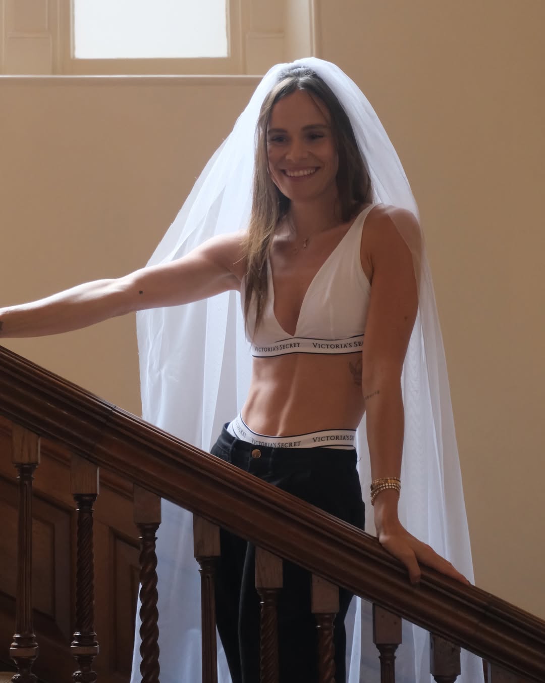 Holly Ramsay posing on a staircase in bridal lingerie and a delicate wedding veil, showcasing her pre-wedding bridal look.