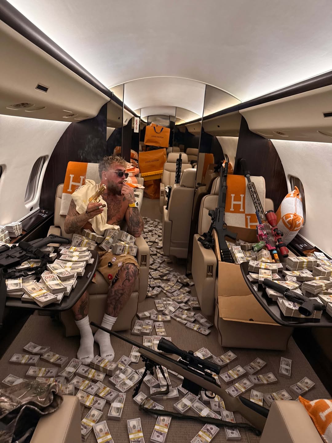 Jake Paul sitting on his private jet after the fight, surrounded by stacks of cash, designer clothes, and firearms, exuding wealth and power.