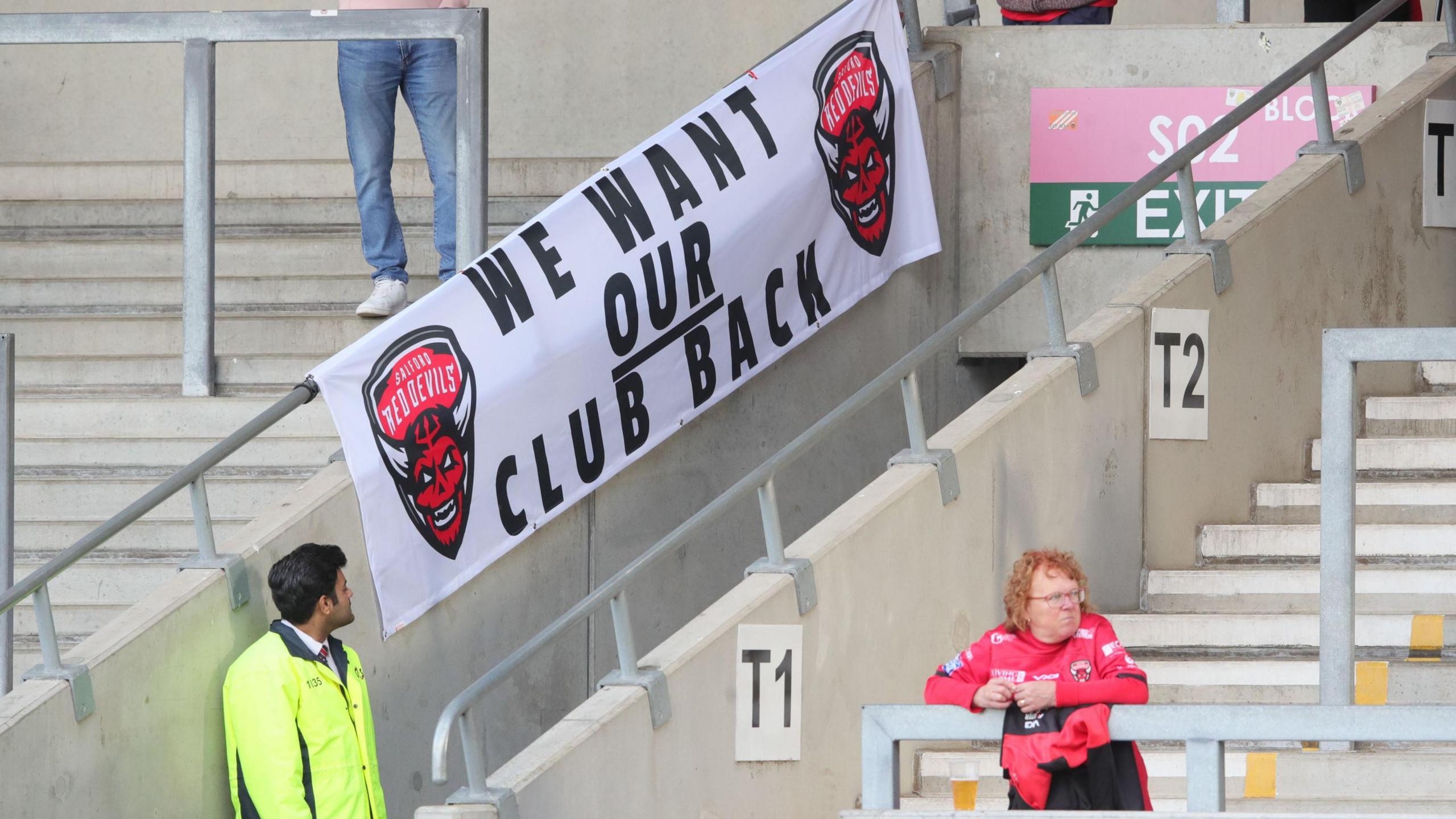 Protest banners displayed inside Salford Red Devils’ stadium, with fans voicing their anger over the club’s financial mismanagement and uncertain future.