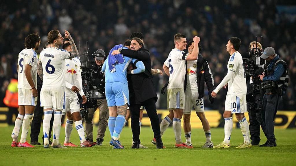 Daniel Farke hugging his Leeds United players at full time, celebrating their 3-1 victory over Chelsea at Elland Road.