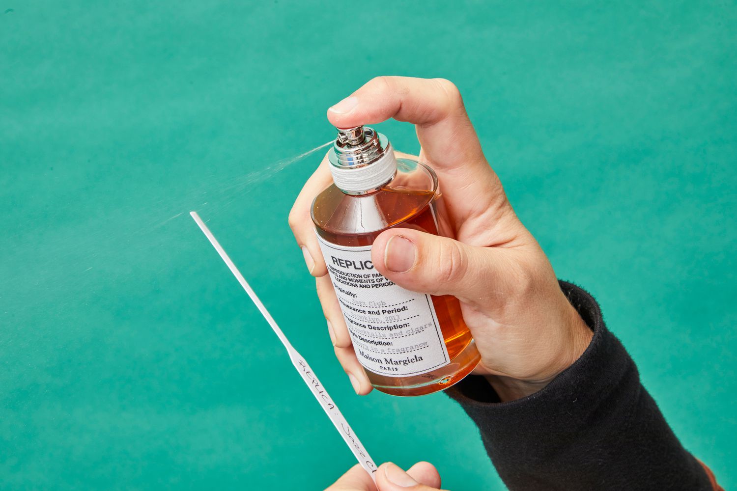 A man spraying cologne onto a scent test stick, evaluating the fragrance before applying it to his skin.