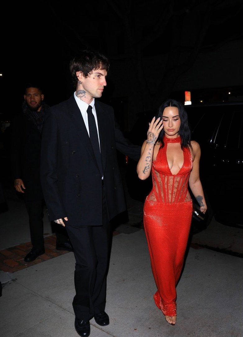 Demi Lovato on the red carpet wearing a dazzling red sequined gown with a plunging neckline, showing off her 50lbs weight loss.