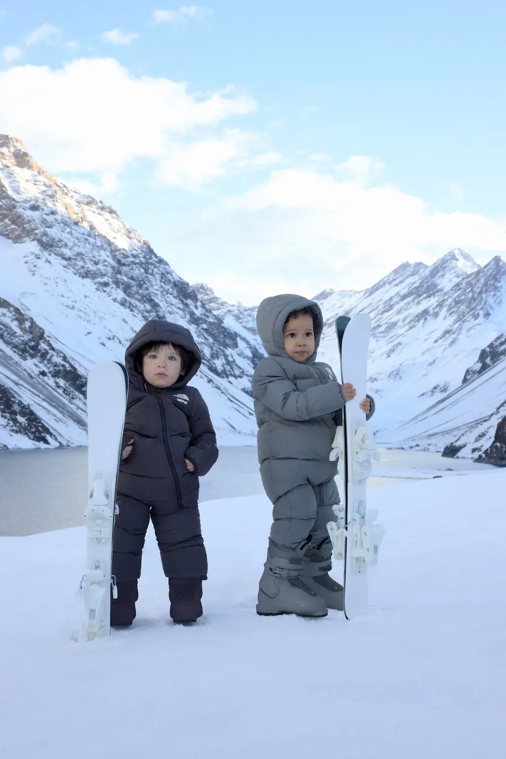 “Two children modeling the SKIMS x The North Face 2.0 kids’ collection, featuring winter coats, hats, and footwear designed for cold-weather style and comfort.
