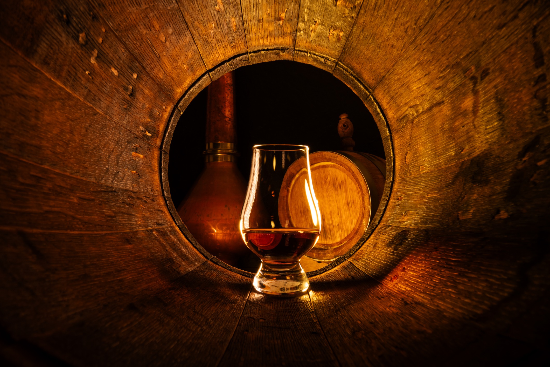 a glass of scotch whiskey in old oak barrel