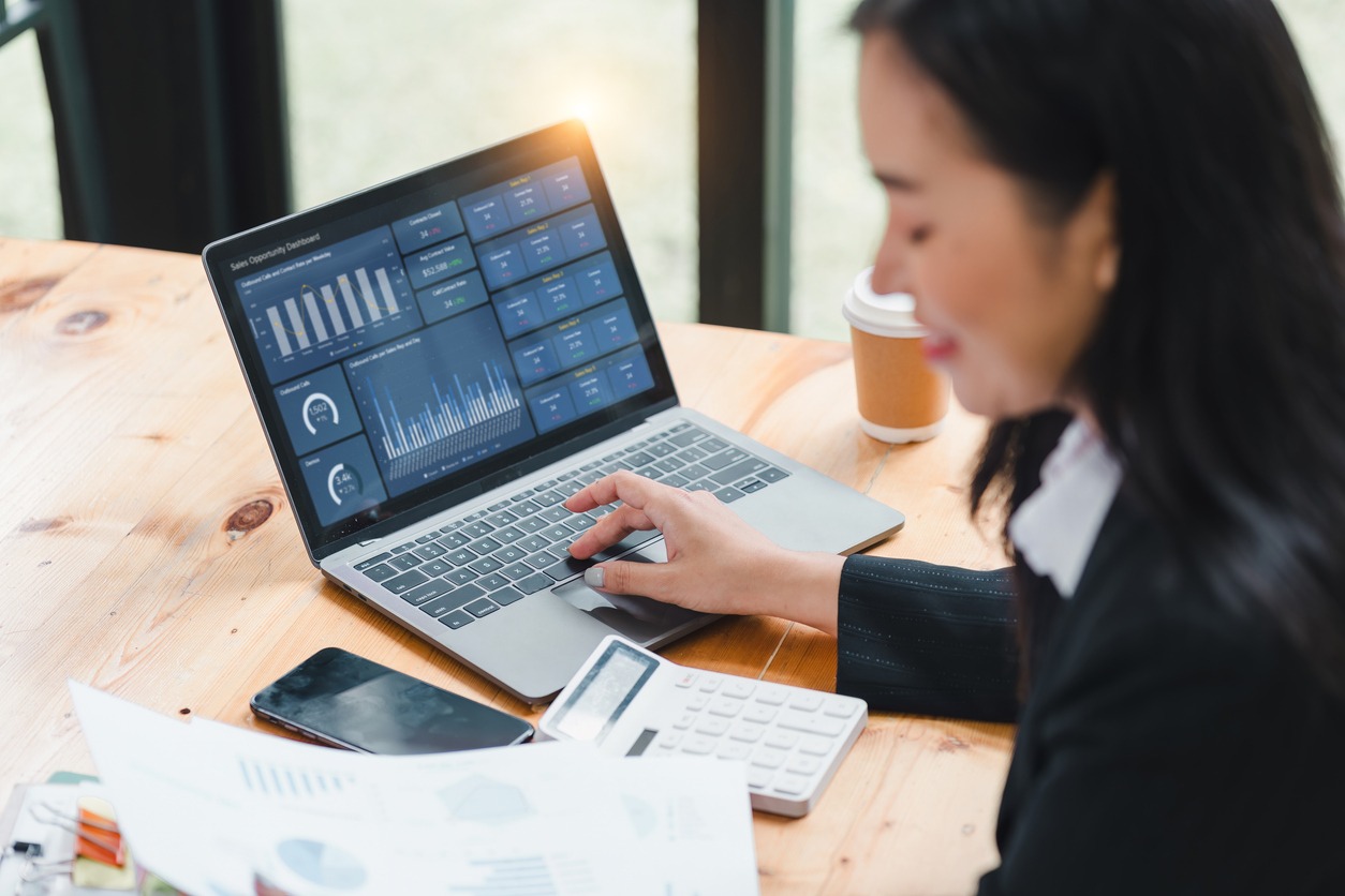 professional woman is working on laptop, analyzing data and charts, surrounded by office supplies. scene conveys focus and productivity in modern workspace