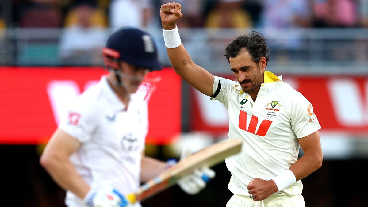Mitchell Starc roars in triumph after dismissing Harry Brook during the second Ashes Test, raising his arms as the ball gleams under the twilight sky.