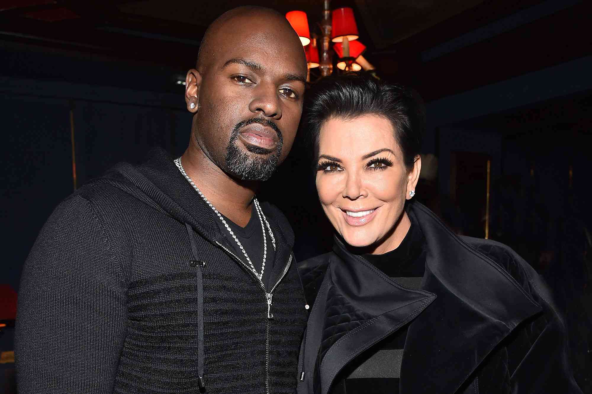 Kris Jenner and Corey Gamble smiling together at an event, both wearing black outfits.