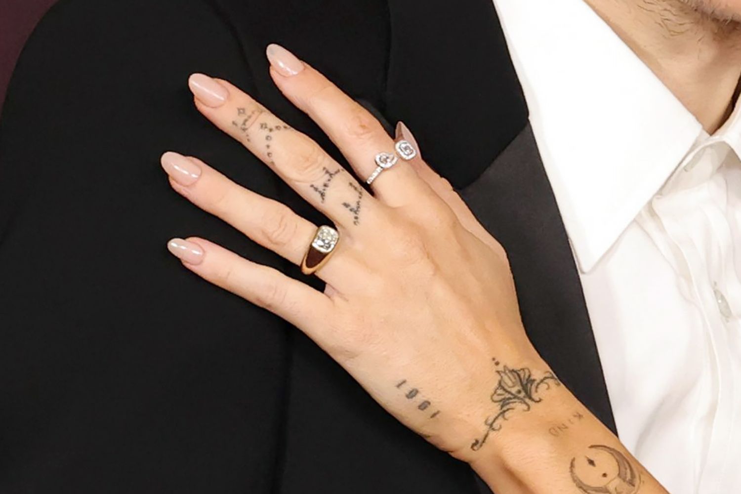 Close-up of Miley Cyrus’ cushion-cut engagement ring, featuring a large diamond set east-to-west on a thick 14-karat yellow gold band.
