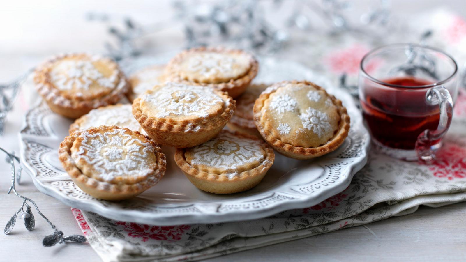Plate of iced mince pies on a festive table, ready to be served during Christmas celebrations.