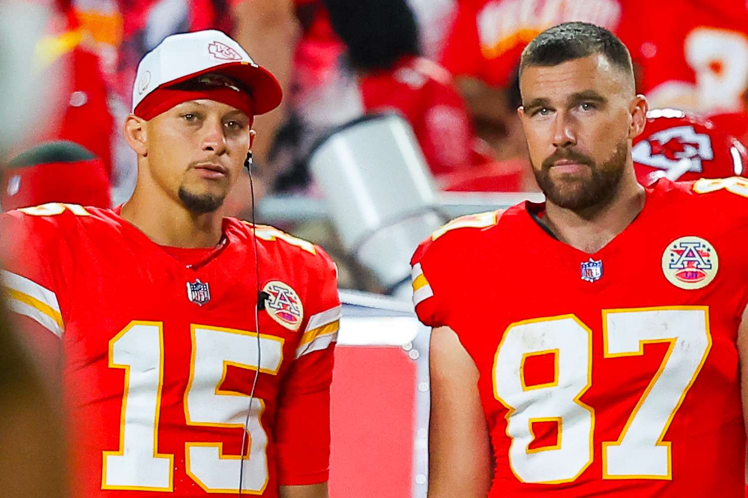 Patrick Mahomes and Travis Kelce standing next to each other on the sideline, chatting with relaxed expressions during a break in the game.