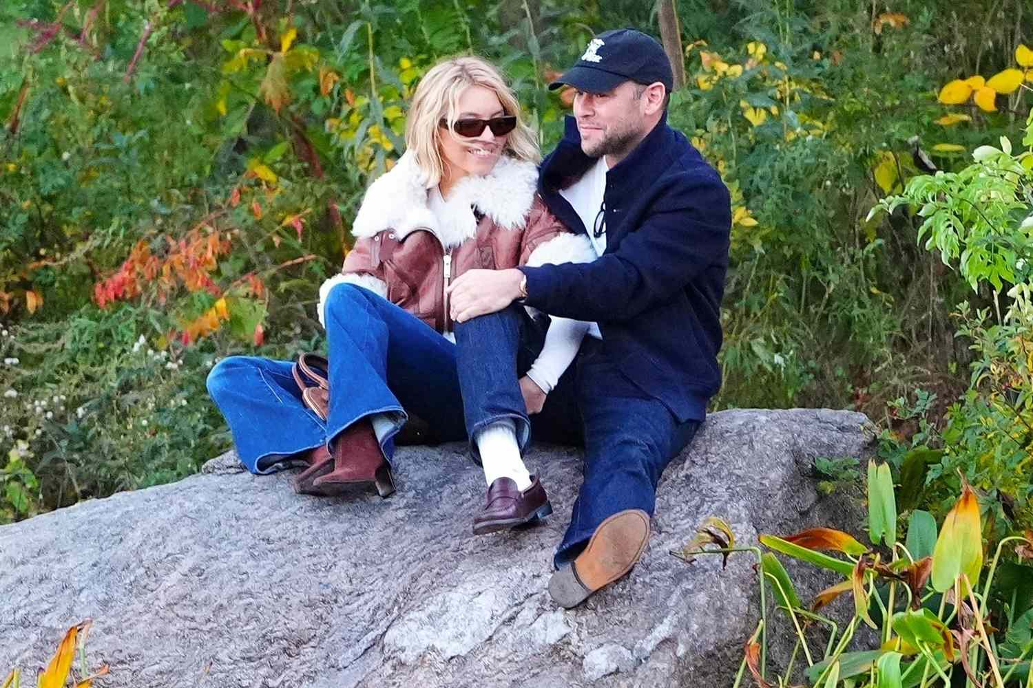 Sydney Sweeney and Scooter Braun sitting on a rock, cuddling during a romantic outdoor date.