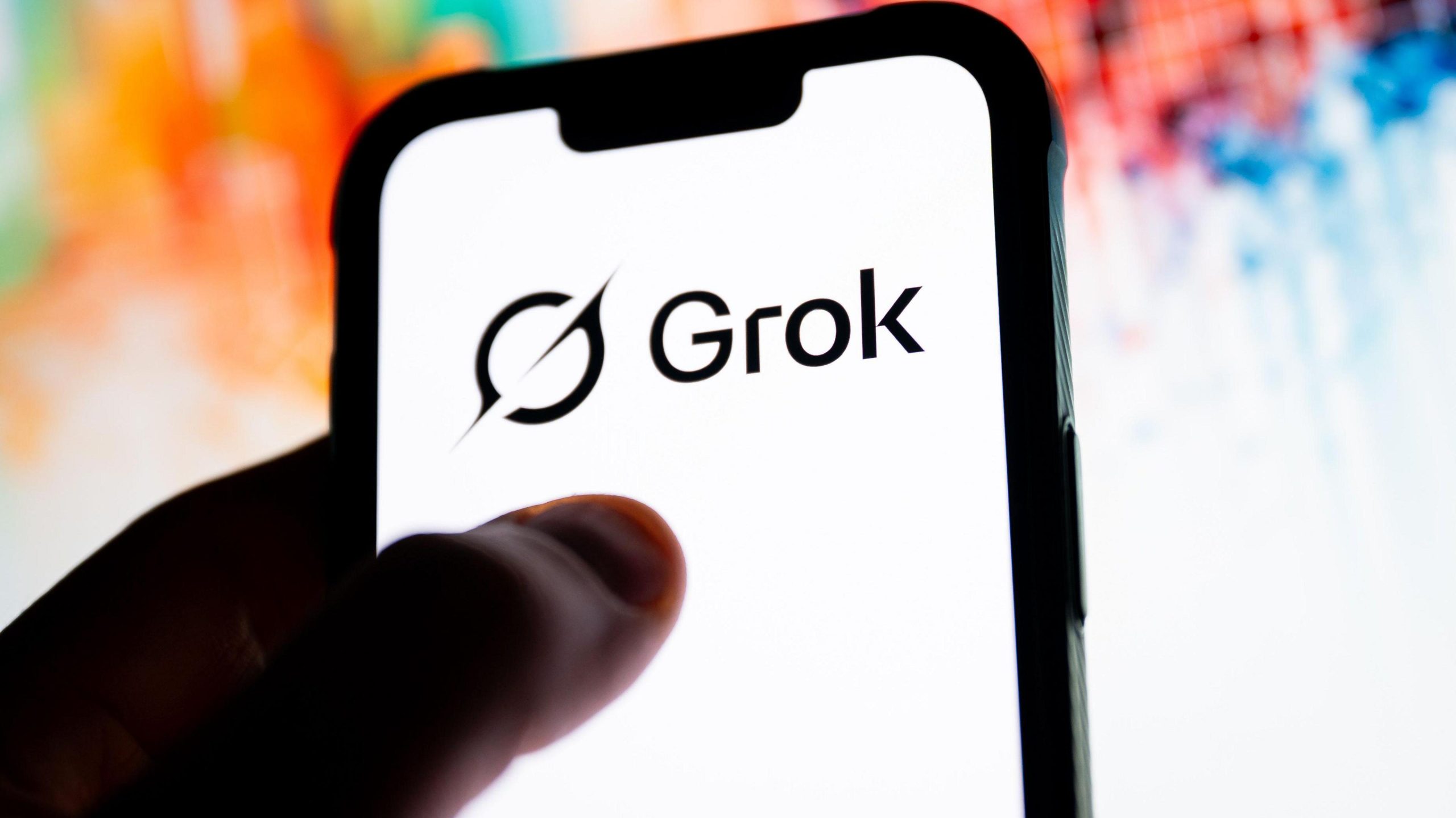 “Grok AI logo displayed on a smartphone screen as regulators investigate the platform over deepfake safety violations.