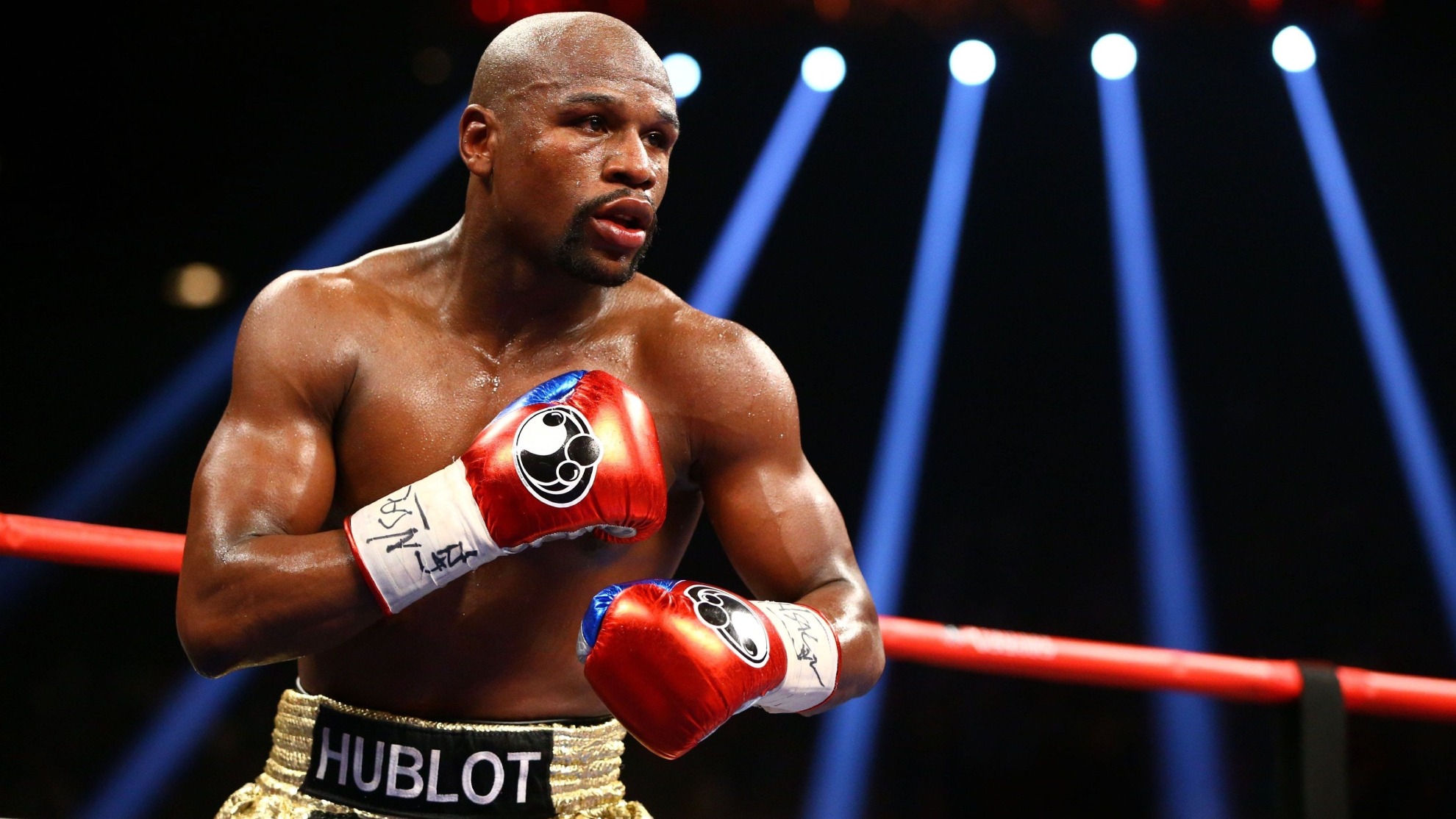 Floyd Mayweather in a defensive boxing stance during a professional fight, showcasing his signature ring style.
