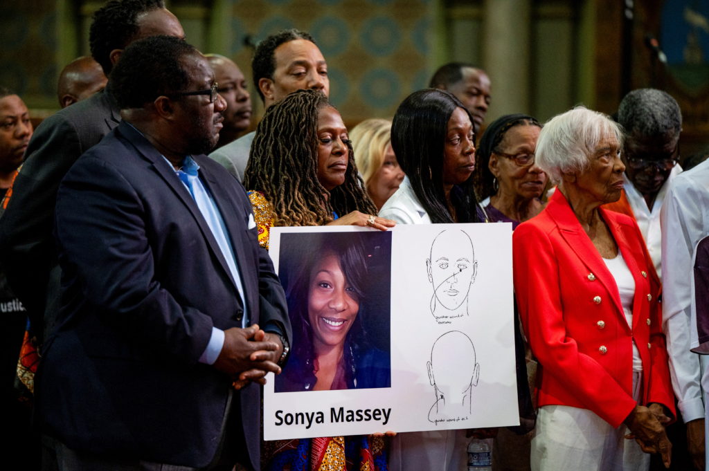 Family members and supporters of Sonya Massey hold a sign with her photo and name during a court proceeding following the sentencing of the former Illinois deputy who killed her.