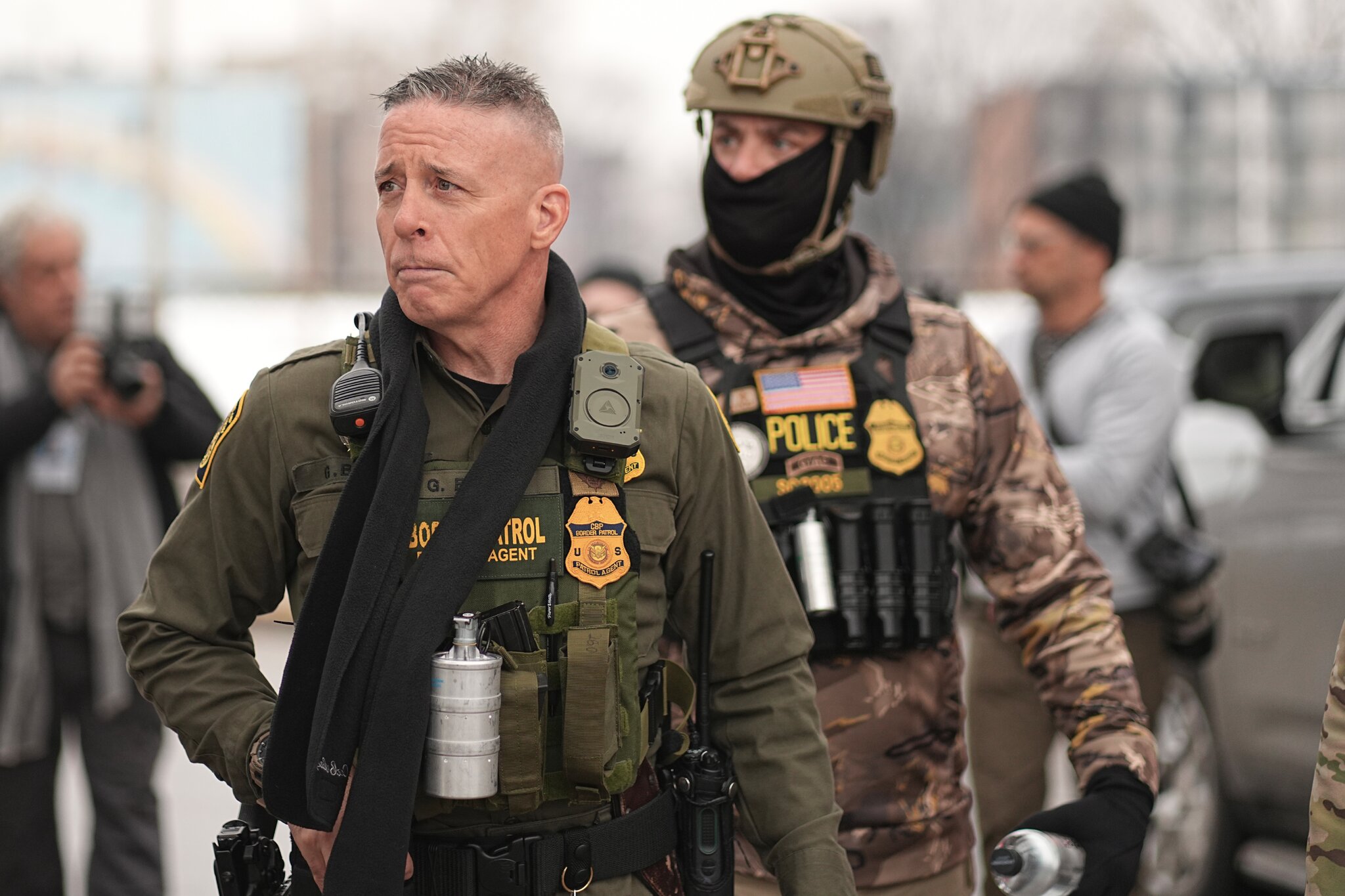 Gregory Bovino walking down a city street flanked by uniformed Border Patrol and ICE agents during an enforcement operation.