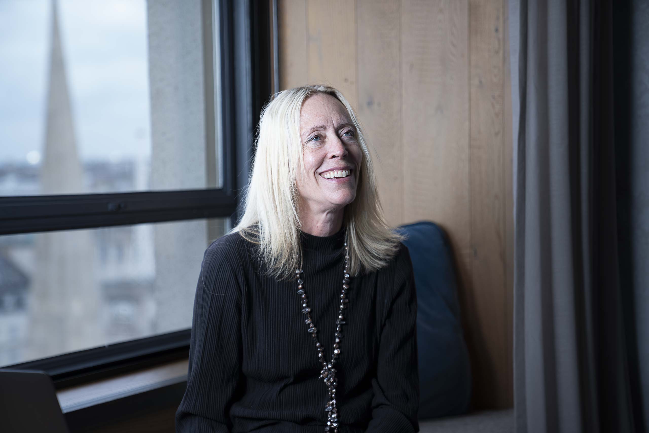 Tina Woods, CEO and founder of Collider Health, seated by a window during a photo shoot