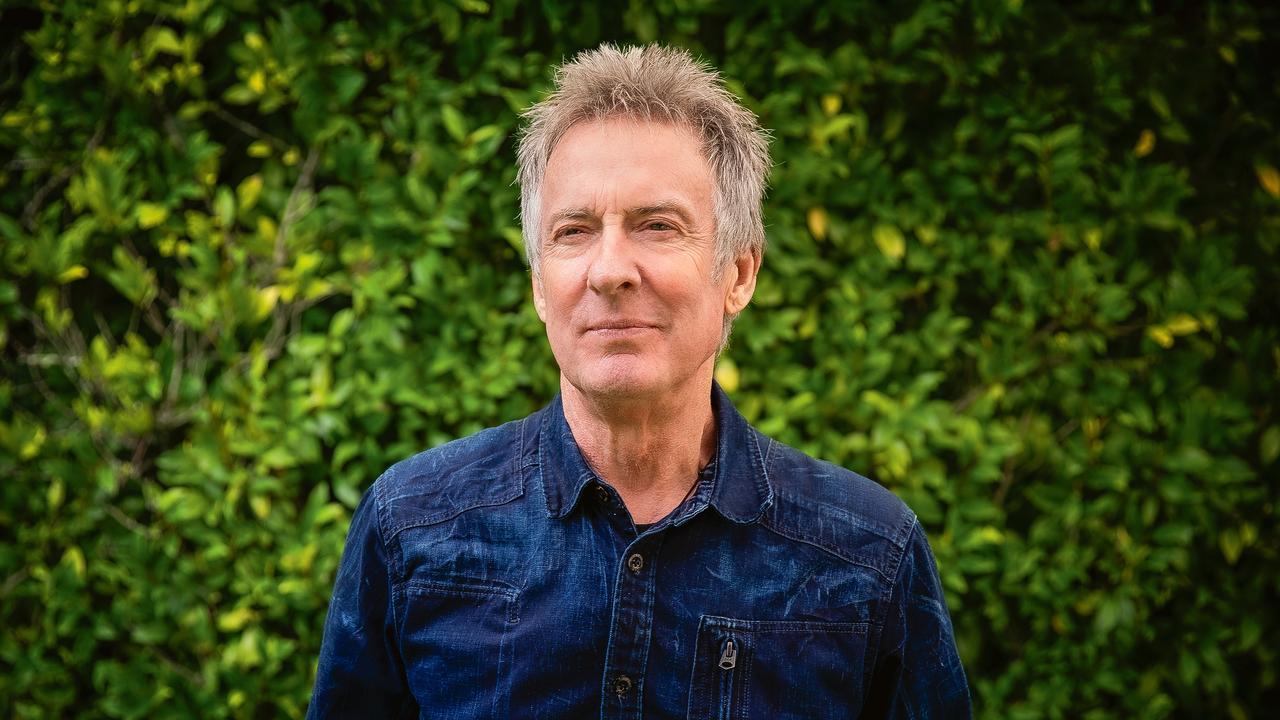 Rob Hirst smiling in his garden at home, surrounded by greenery.