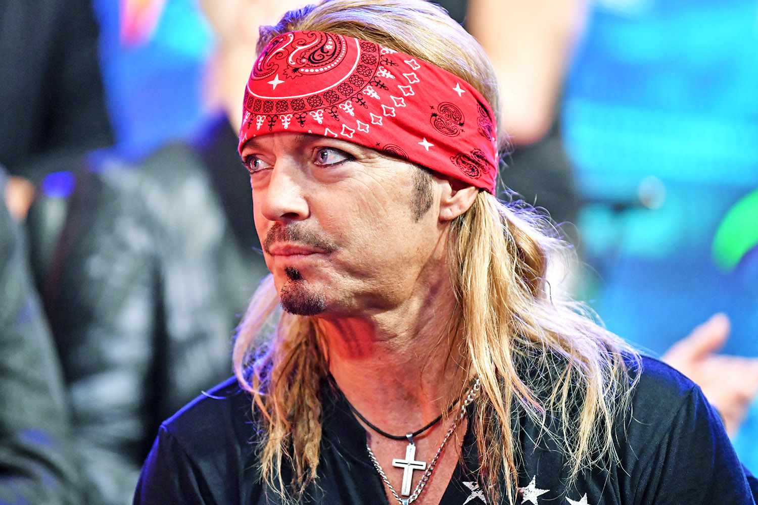 Bret Michaels wearing a red bandana and cross necklace, photographed at a public event.