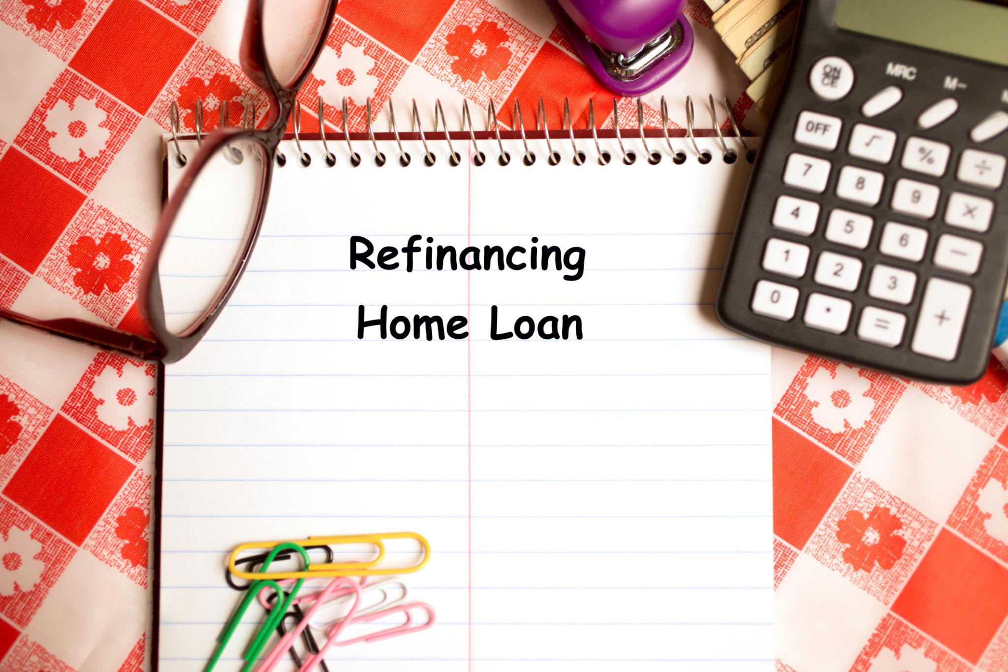 Home refinance paperwork on a kitchen table as mortgage rate uncertainty builds