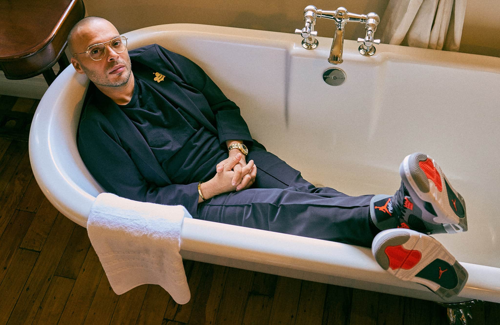 Richie Akiva posing in a tuxedo while reclining in a bathtub, looking relaxed and playful.