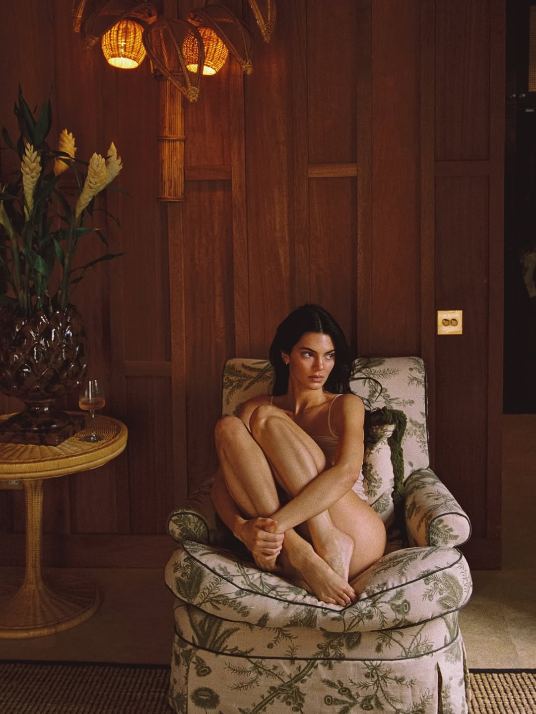 Kendall Jenner sitting in an armchair, holding her legs, wearing minimal clothing, in her Instagram photoshoot addressing cosmetic surgery rumors.