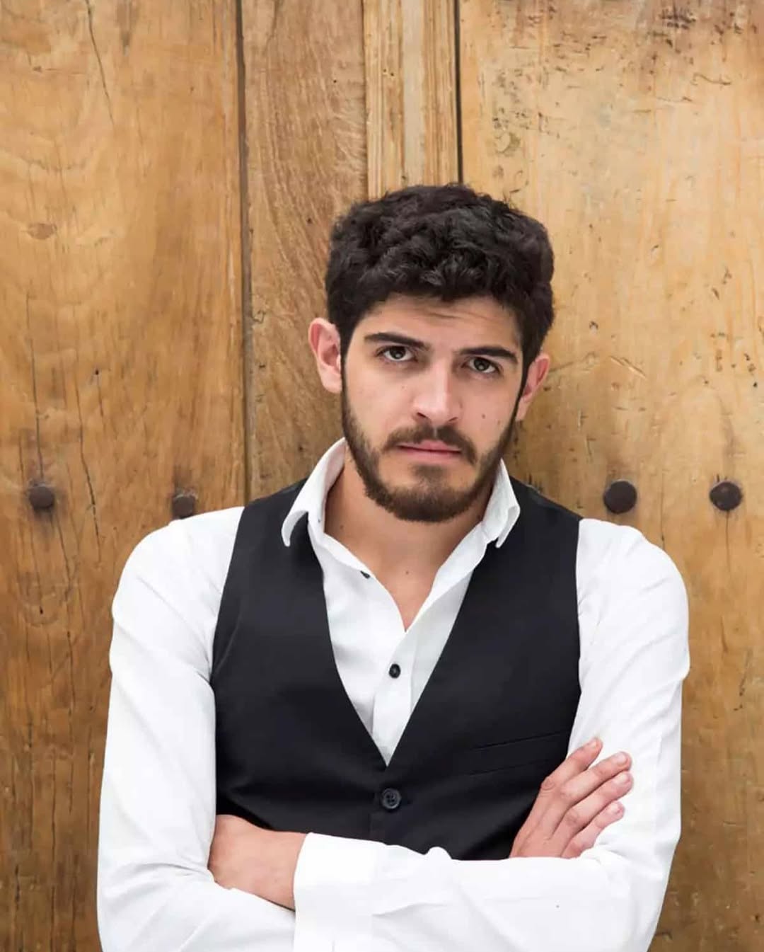 Alexis Ortega posing in a white shirt and black blazer, looking confidently at the camera during a professional photoshoot.