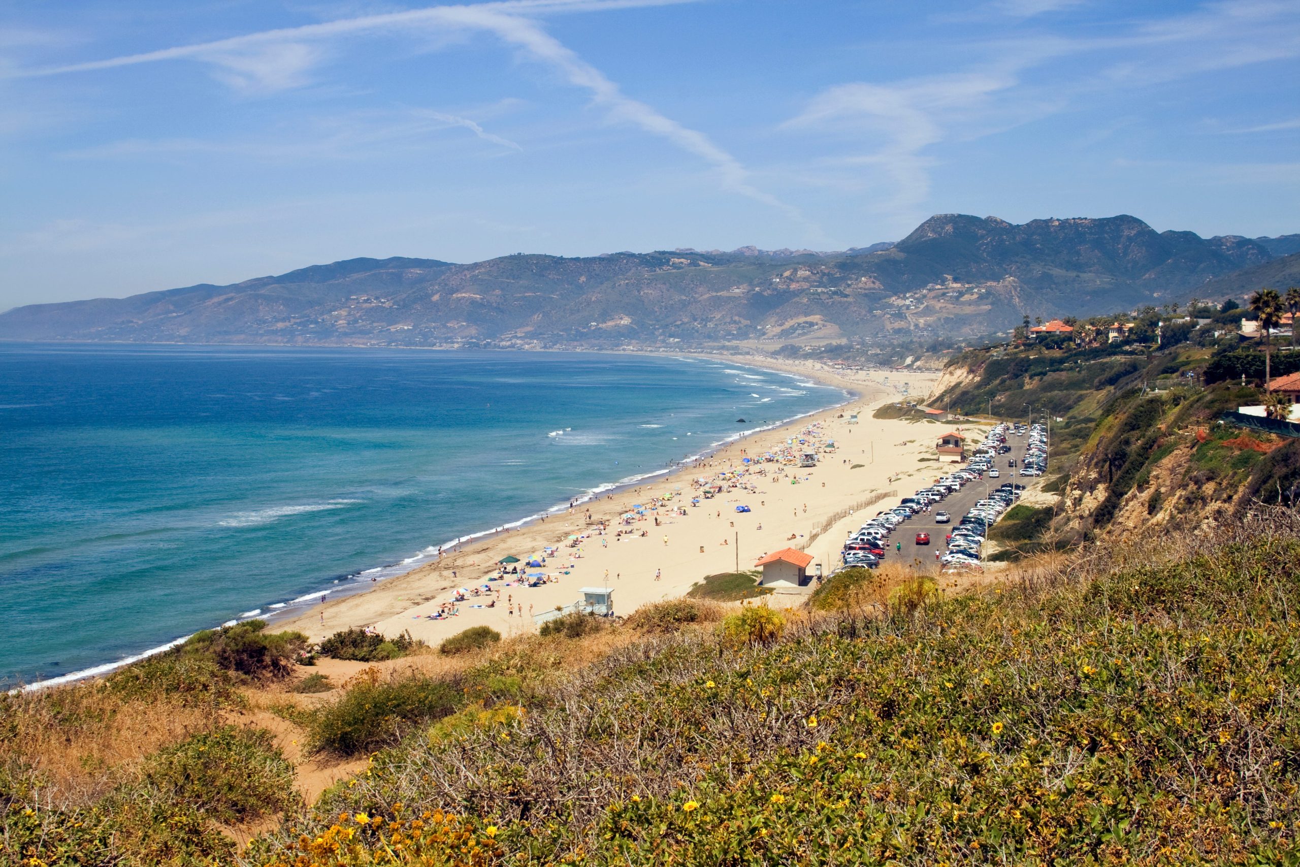 Coastal view of Malibu Beach near Kamala Harris’s Point Dume home, showing the Pacific Ocean, sandy shoreline, and the surrounding bluffside landscape.