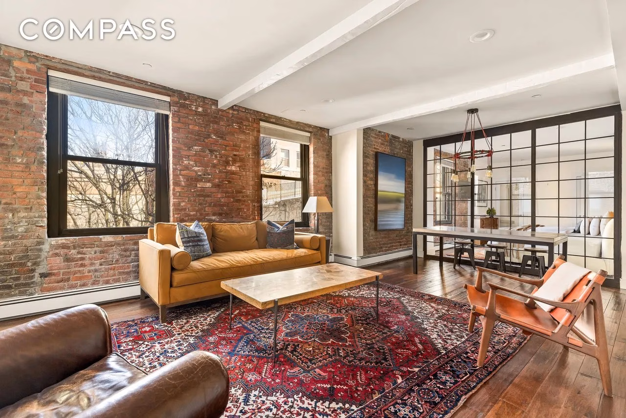 Living area of Jim Curtis’s Manhattan apartment, showcasing exposed brick walls, loft-style design, and views of the Brooklyn Bridge.