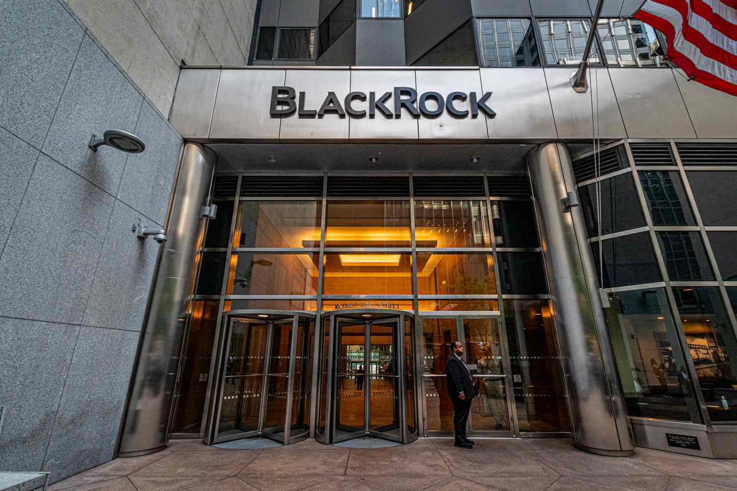 Entrance to the BlackRock headquarters with an American flag waving in front of the building.