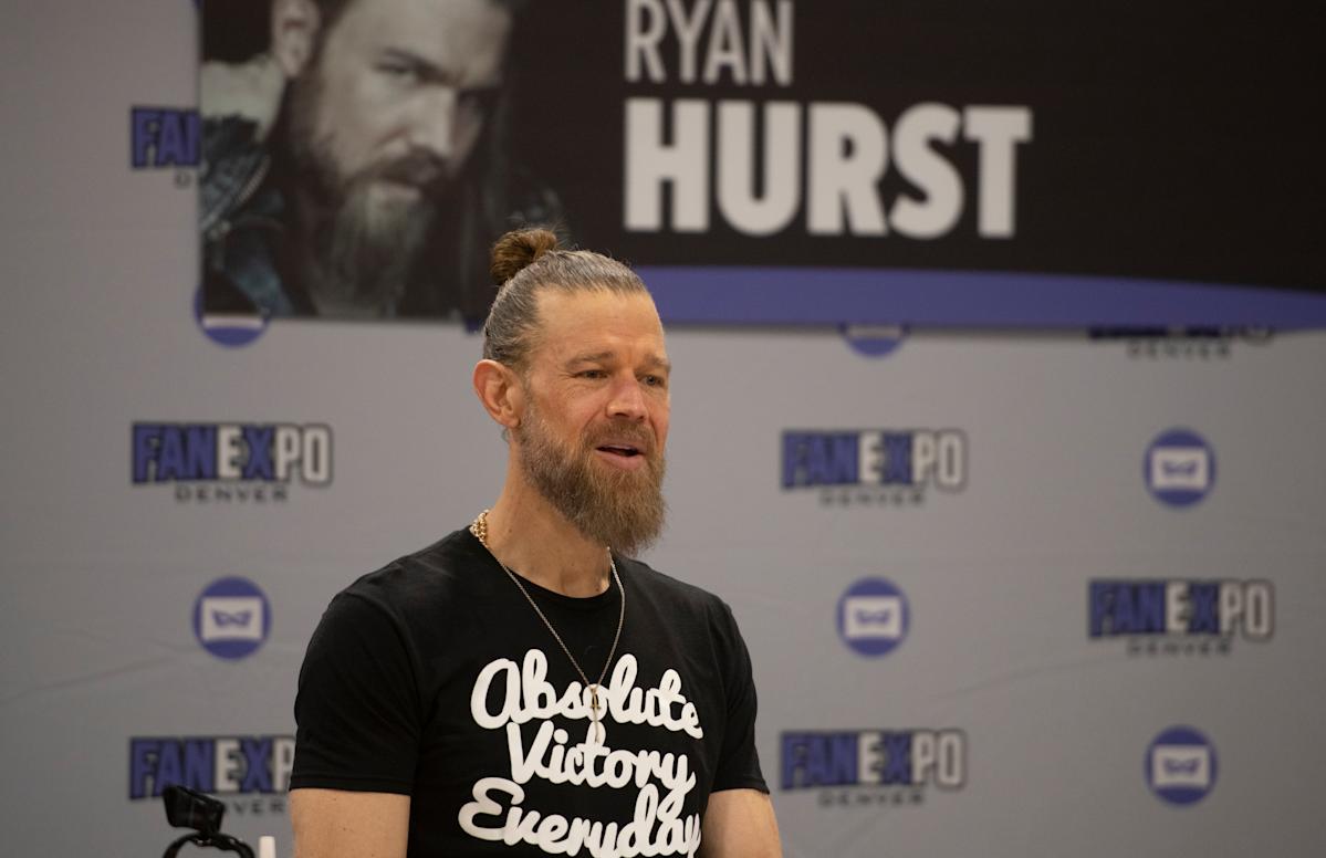 Ryan Hurst sitting at a table during a fan meet-and-greet, smiling and interacting with attendees.