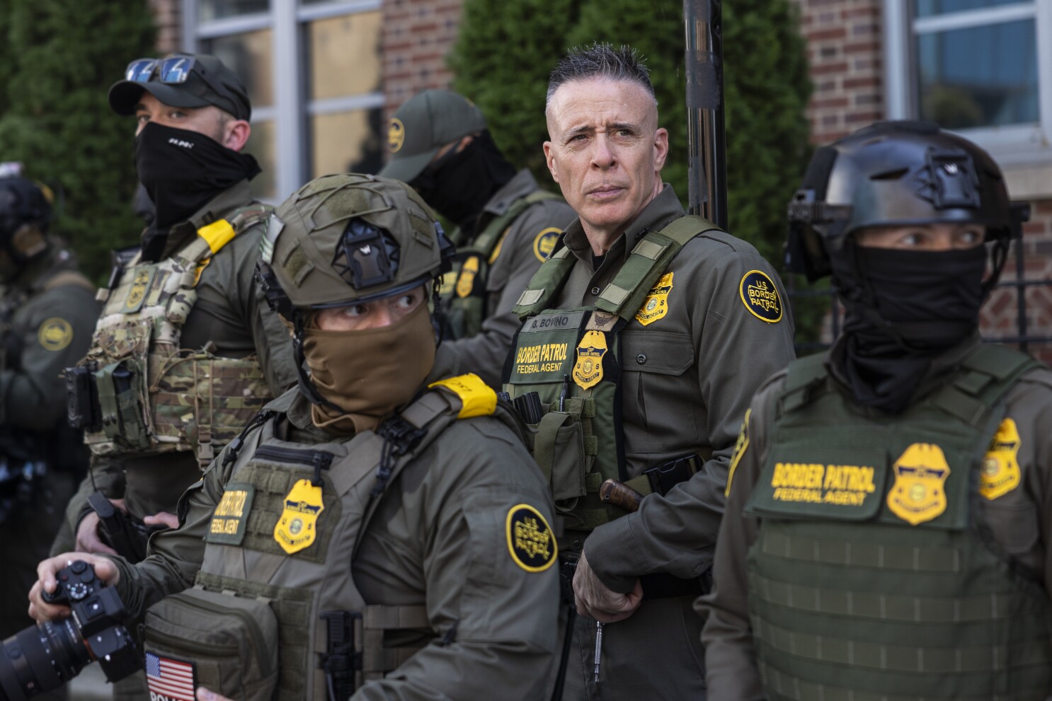 Gregory Bovino standing with a group of uniformed ICE agents during a coordinated immigration enforcement operation.