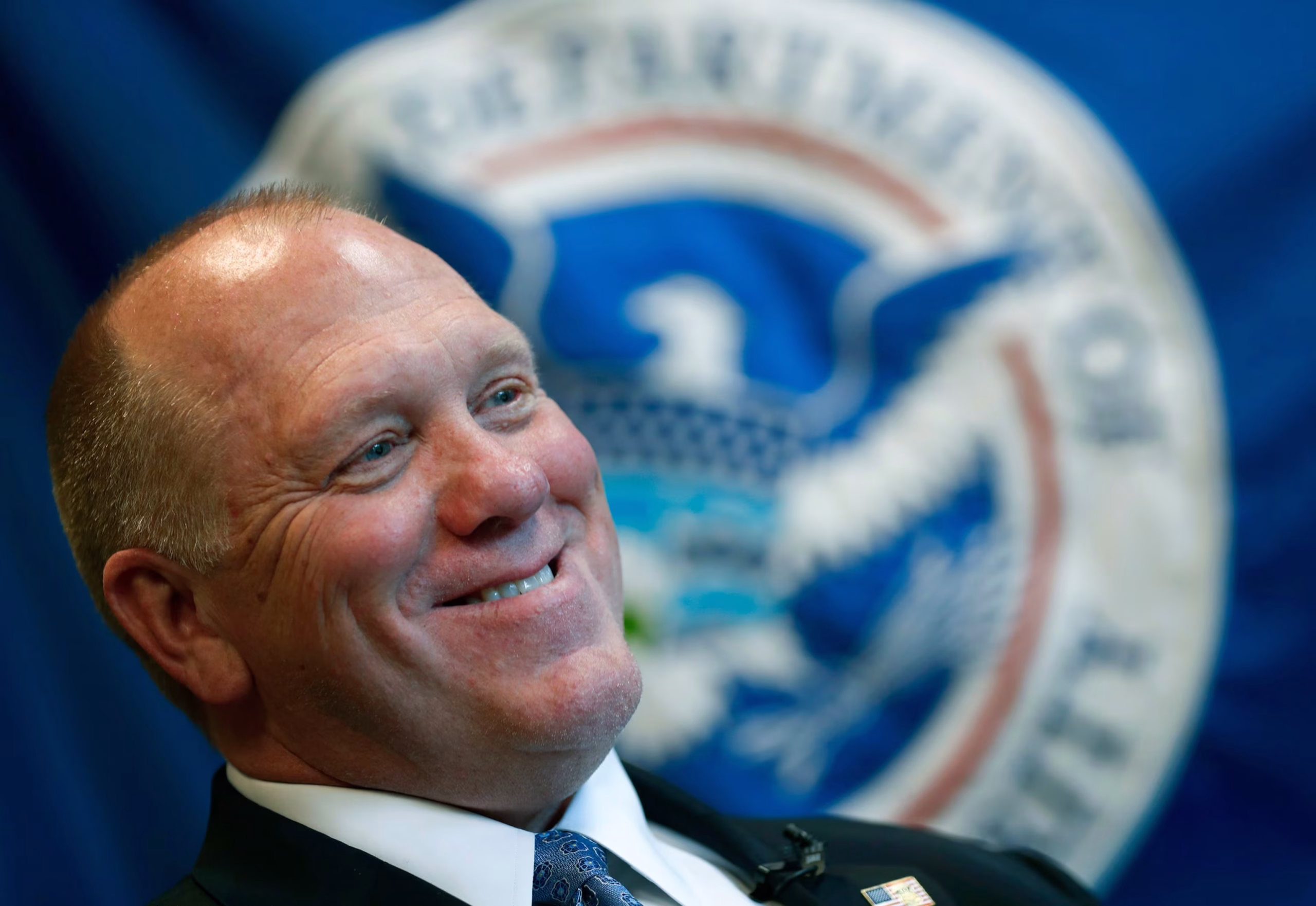 Tom Homan, White House border czar, speaks at a public event with a Department of Homeland Security seal visible in the background.
