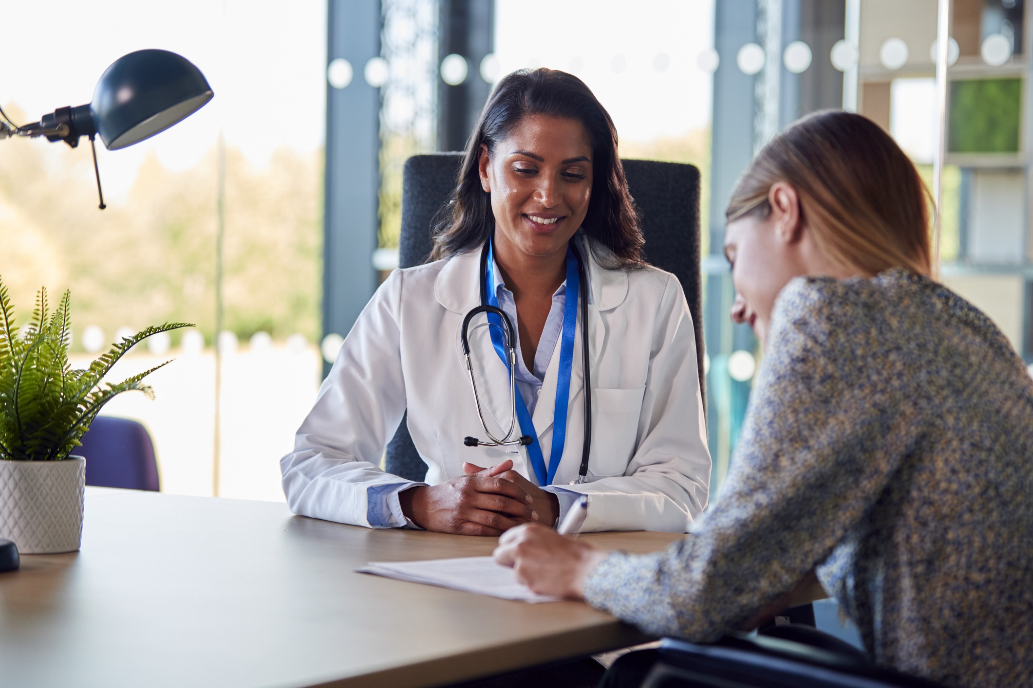 female doctor getting woman patient to sign consent form in hospital office