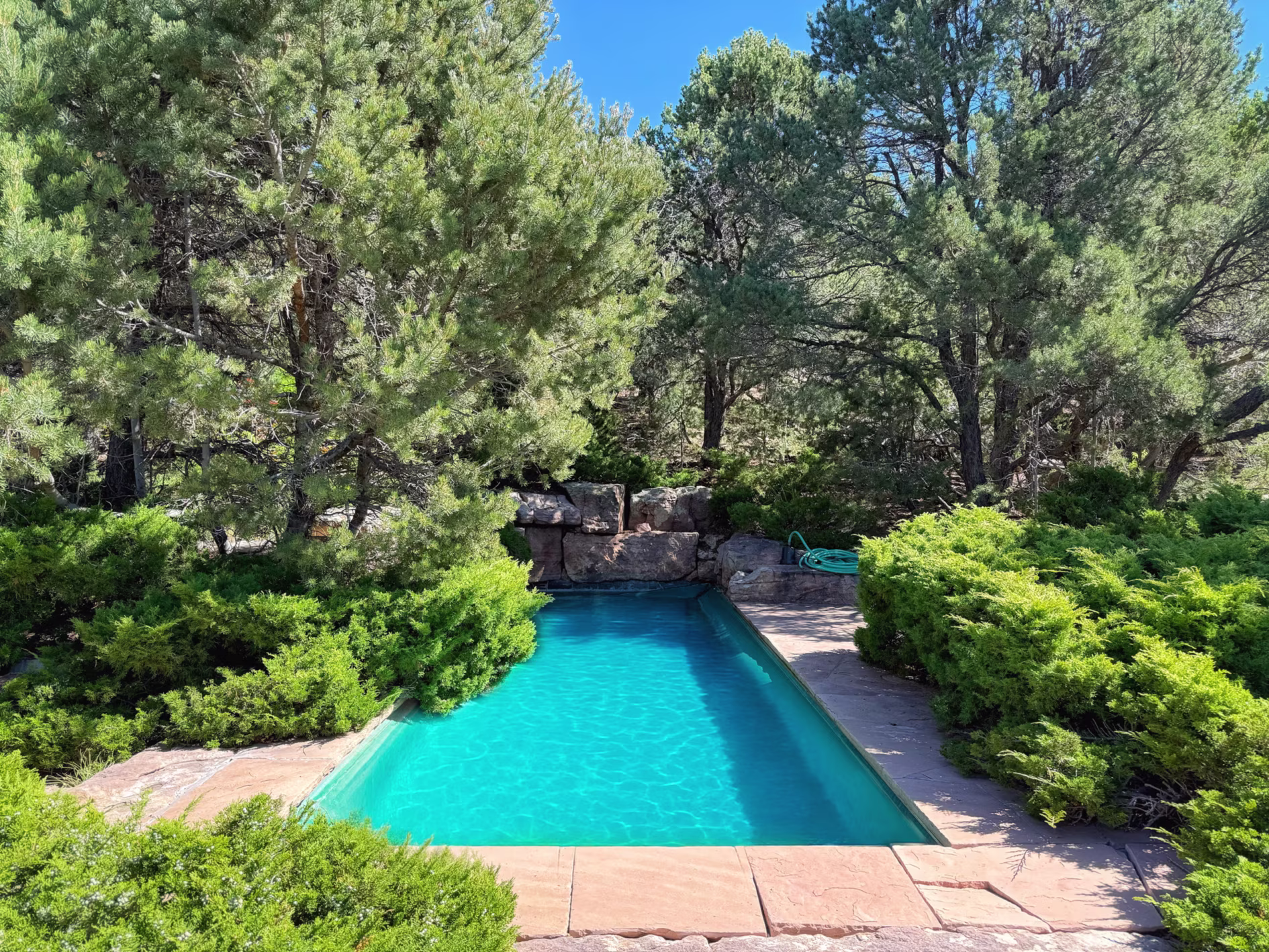 Private lap pool at Gene Hackman’s Santa Fe estate, surrounded by natural stone and woodland on the 53-acre property.